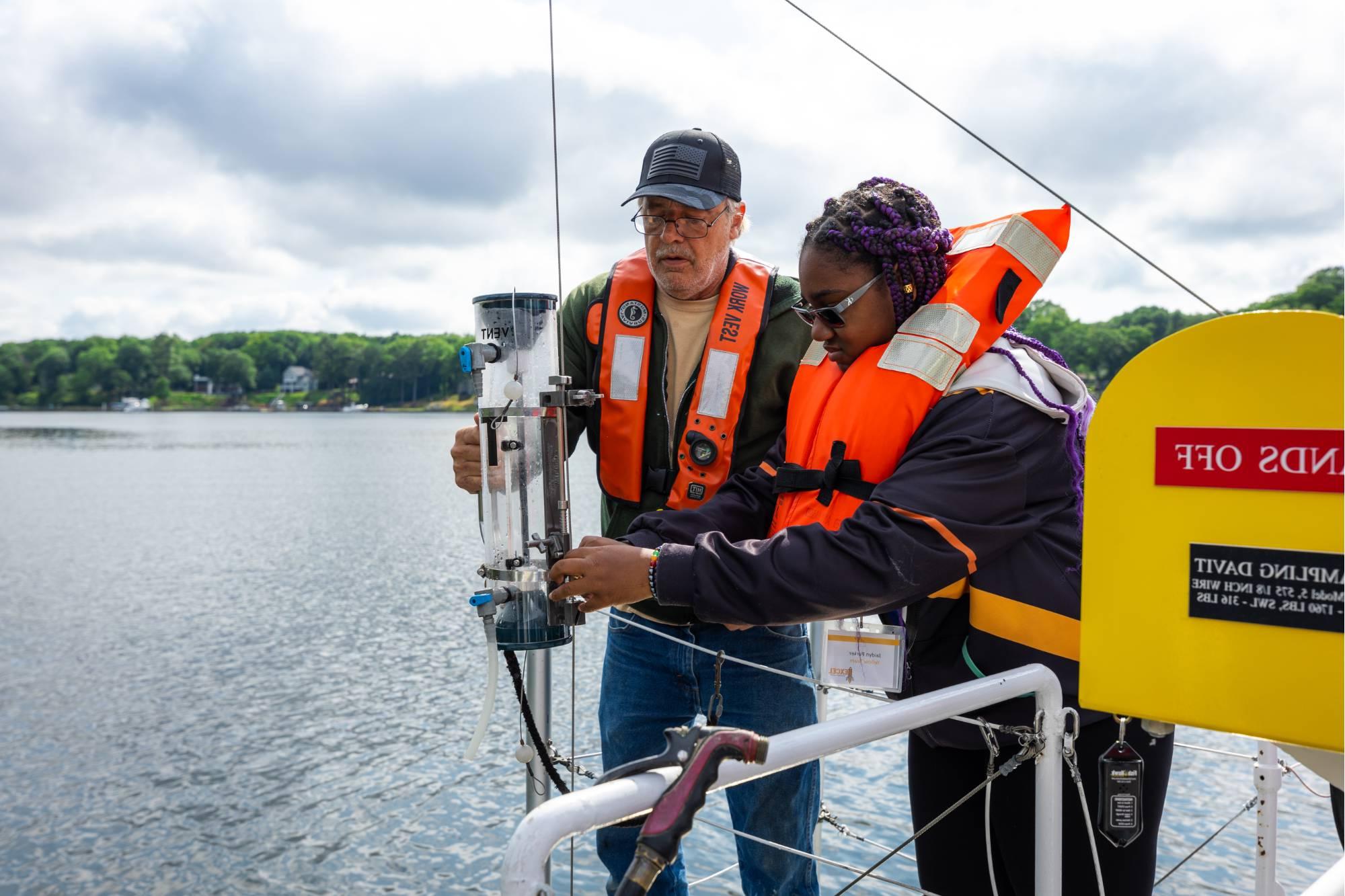 A student and deckhand collect a sample of Spring Lake water during a cruise on the D.J. Angus